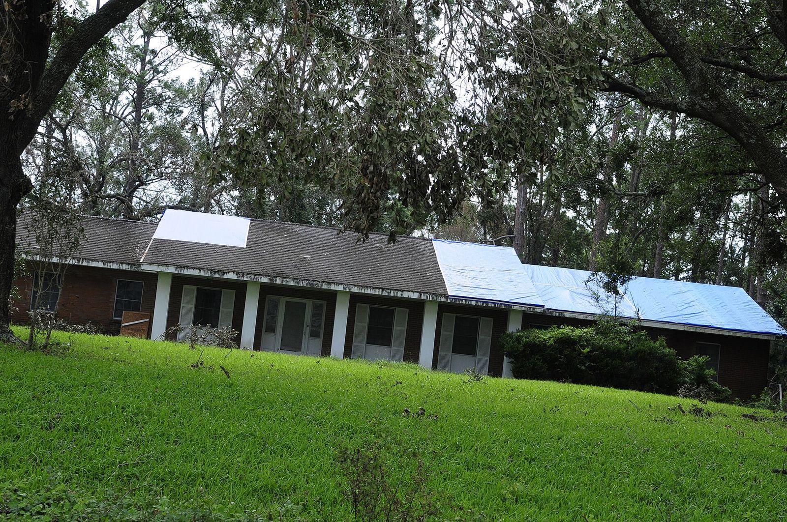 House with a blue tarp on the roof after a storm