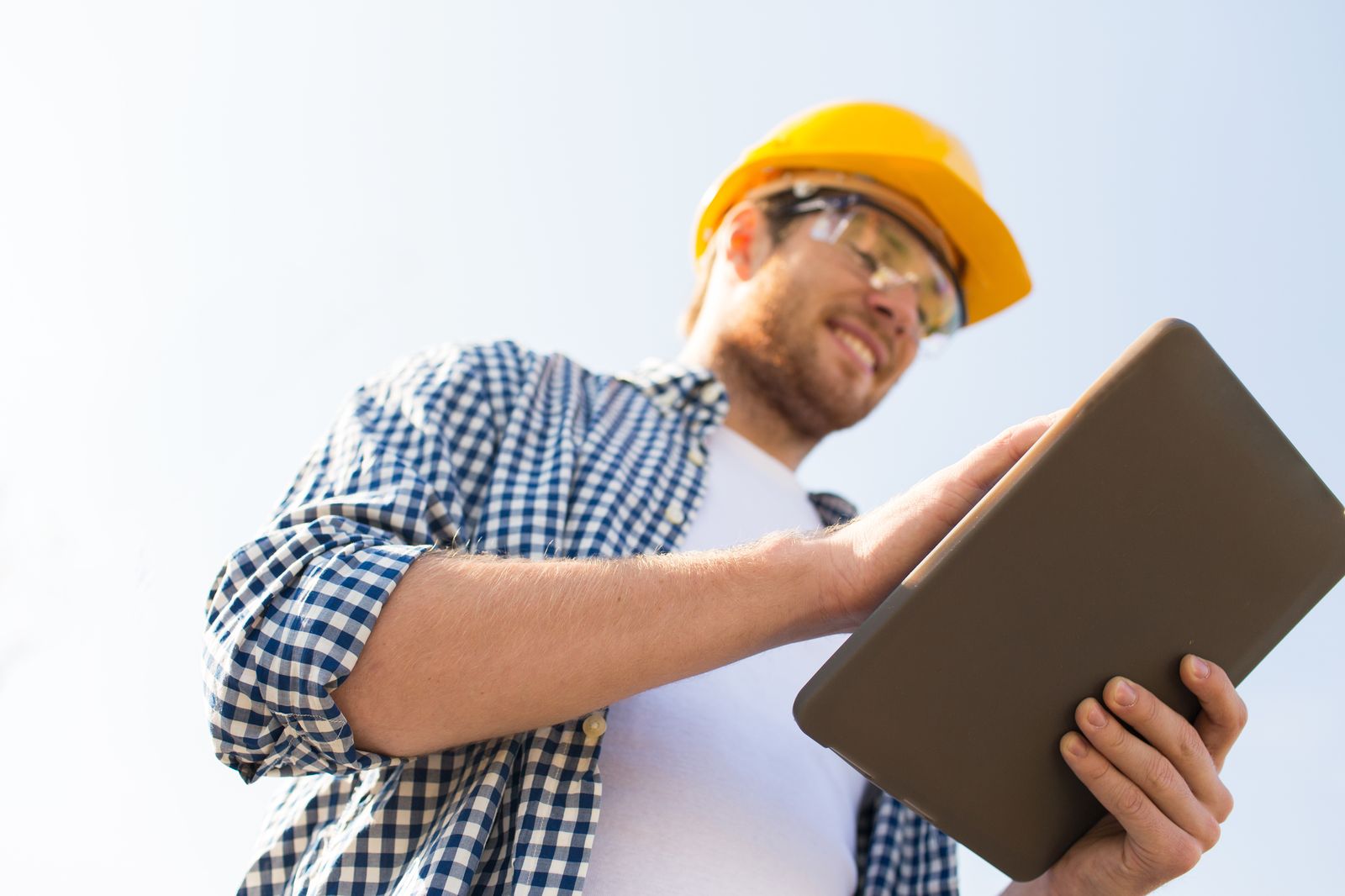 Prairie Fox Roofing crew lead on a roof checking the day's plan on a tablet