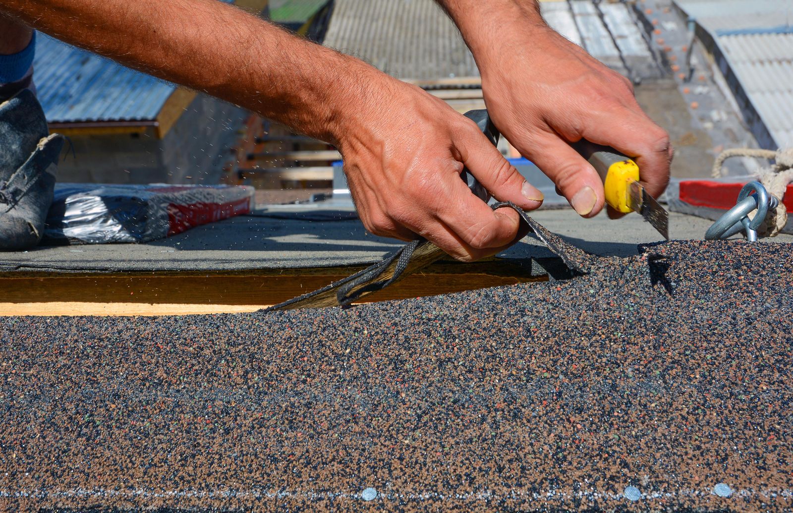 Roofer cutting shingles to fit a valley