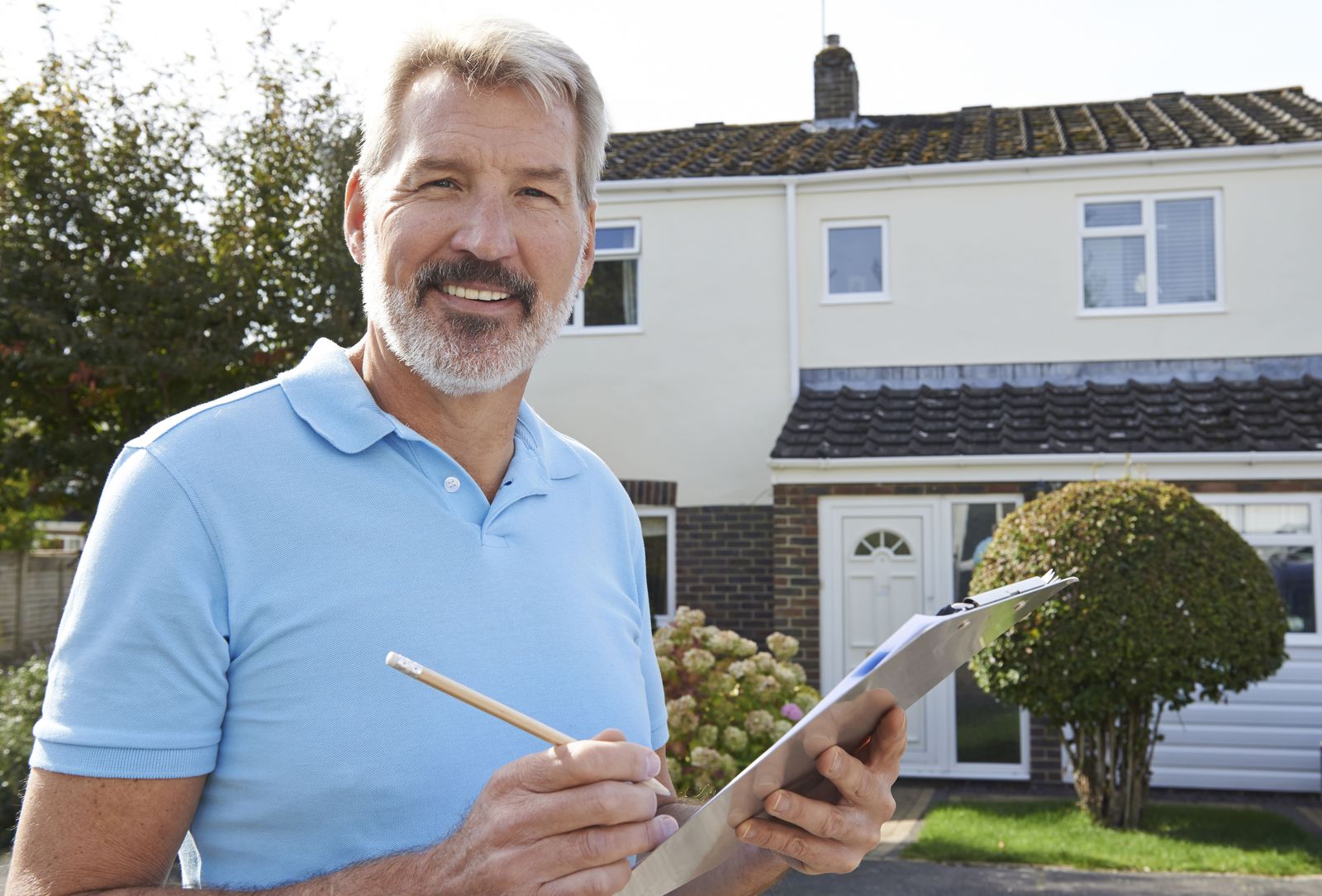 Marco, owner of Prairie Fox Roofing, in front of a house with a clipboard
