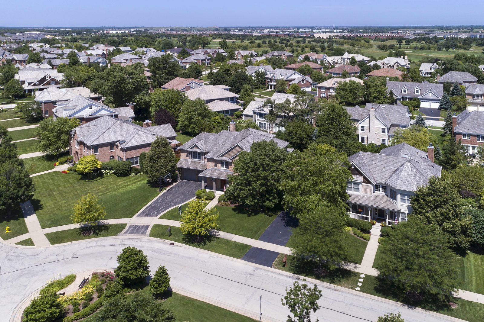 Aerial view of a suburban block of single-family homes with new shingle roofs
